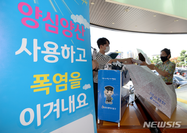 [광주=뉴시스] 김혜인 기자 = 광주 동구청 직원들이 28일 오후 광주 동구청사에서 '양심양산 대여소'를 마련하고 있다.2021.07.28.hyein0342@newsis.com