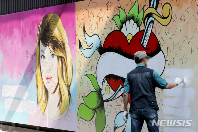 [서울=뉴시스] 김병문 기자 = 30일 오전 서울 종로구 윤석열 전 검찰총장의 아내 김건희 씨를 비방하는 내용의 벽화가 그려진 서점 외벽에서 서점 관계자가 벽화 속 문구를 지우고 있다. 2021.07.30. dadazon@newsis.com