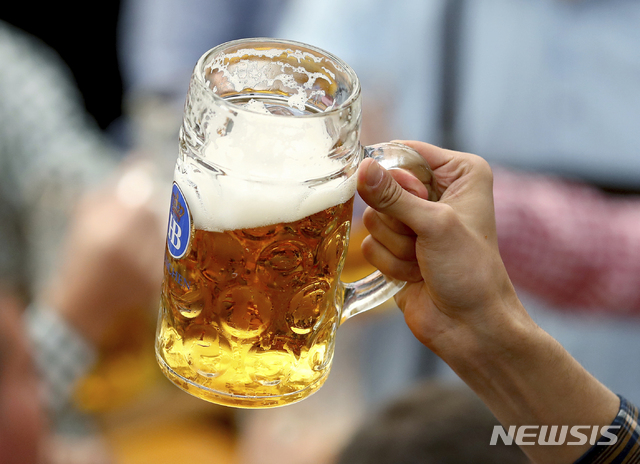 FILE - In this Sept.21, 2019 file photo a guest holds glasses of beer during the opening of the 186th 'Oktoberfest' beer festival in Munich, Germany. German beer sales in this year’s first half were 2.7% lower than a year earlier. They were dragged lower by closures of bars and restaurants that stretched through winter and into spring. (AP Photo/Matthias Schrader, file)