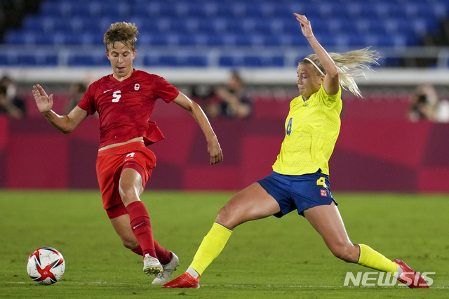 [도쿄=AP/뉴시스]캐나다의 수비형 미드필더 퀸(왼쪽)이 지난 6일 스웨덴과의 도쿄올림픽 여자축구 결승전에서 스웨덴의 한나 글라스와 공을 다투고 있다. 캐나다가 승부차기 끝에 우승하면서 퀸은 사상 최초로 성전환자이자 넌바이너리로 올림픽 금메달리스트가 됐다. 2021.8.8