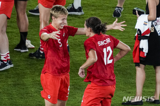 [도쿄=AP/뉴시스]캐나다의 수비형 미드필더 퀸(왼쪽)이 지난 6일 스웨덴과의 도쿄올림픽 여자축구 결승전에서 스웨덴을 승부차기 끝에 누르고 우승한 뒤 동료 크리스틴 싱클레어와 승리를 축하하고 있다. 퀸은 사상 최초로 성전환자이자 넌바이너리로 올림픽 금메달리스트가 됐다. 2021.8.8