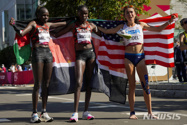 Gold medalist Peres Jepchirchir, left, of Kenya, stands with silver medalist and compatriot Brigid Kosgei, centre, and bronze medalist Molly Seidel, right, of the United States, following the women&#039;s marathon at the 2020 Summer Olympics, Saturday, Aug. 7, 2021, in Sapporo, Japan (AP Photo/Eugene Hoshiko)