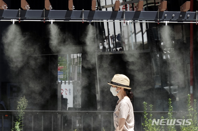 [도쿄=AP/뉴시스] 10일 일본 도쿄에서 코로나19 확산 방지를 위해 마스크를 쓴 한 여성이 무더위를 식히는 쿨링존을 지나가고 있다. 일본 기상청은 수도권 지역 기온이 38도까지 오르면서 무더운 날씨가 이어지고 있다고 밝혔다. 2021.08.10