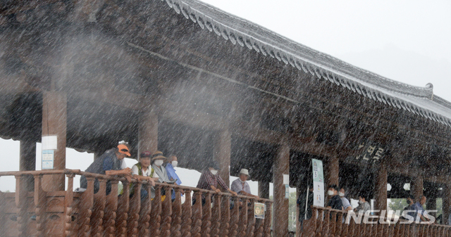 [전주=뉴시스] 김얼 기자 = 전북 전주시에 갑작스러운 집중호우가 내리기 시작한 12일 오후 전주한옥마을 남천교 청연루 처마 밑에서 관광객들이 비를 피하고 있다. 2021.08.12. pmkeul@newsis.com