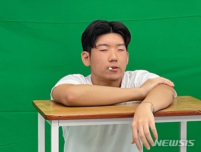 [의정부=뉴시스] 의정부고등학교 학생자치회가 공개한 졸업사진. 한 학생이 '2020도쿄올림픽' 국가대표 야구선수 강백호가 경기 중 덕아웃에 앉아 있는 모습을 패러디 하고 있다. (사진=의정부고 학생자치회 제공)