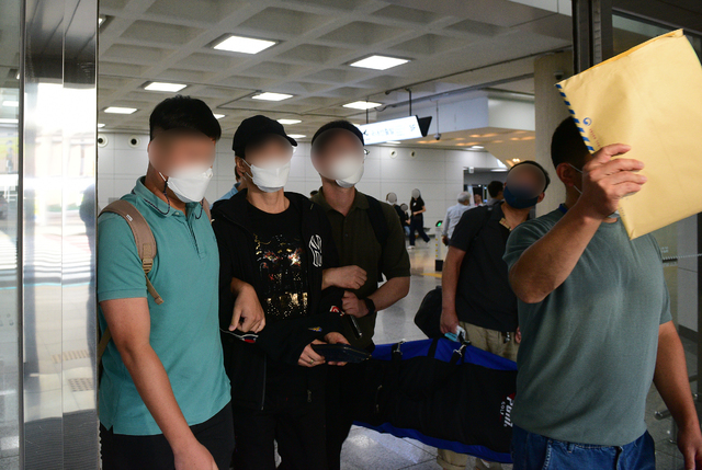 [제주=뉴시스] 우장호 기자 = 제주 지역 장기미제 '이승용 변호사 살인 사건' 핵심 피의자로 지목된 A(55·왼쪽 두번째)씨가 지난 18일 오후 제주국제공항 1층 도착장에서 경찰에 의해 송환되고 있다. 경찰은 A씨를 1999년 11월5일 발생한 이 변호사 살인사건의 교사범으로 보고 체포영장을 발부받았다. 캄보디아에 불법체류 중이던 A씨는 현지 경찰과 인터폴 적색수배에 따른 강제추방이 결정돼 국내로 송환됐다. 2021.08.20. woo1223@newsis.com *재판매 및 DB 금지