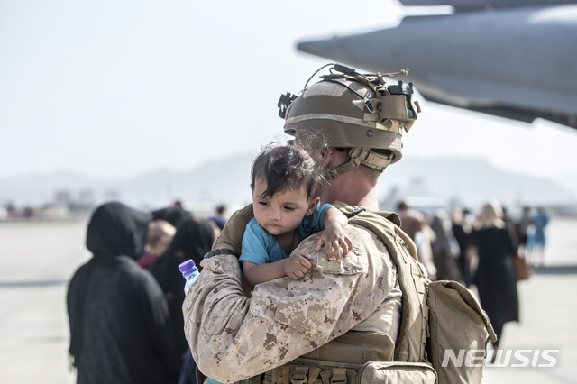 [카불=AP/뉴시스] 21일(현지시간) 아프가니스탄 카불의 하미드 카르자이 국제공항에서 아프간 대피 작전 중인 미 해병대 병사가 한 아프간 아이를 안아 달래고 있다. 2021.08.23.