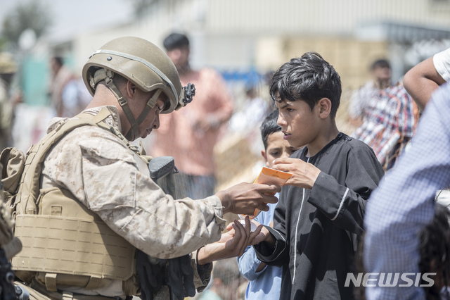 [카불=AP/뉴시스] 22일(현지시간) 아프가니스탄 카불의 하미드 카르자이 국제공항에서 아프간 대피 작전 중인 미 해병대원이 한 아프간 어린이에게 선크림을 나눠주고 있다. 8월 31일로 제시된 아프간 대피 시한을 연장해야 한다는 목소리가 높아지자 탈레반은 "시한을 준수하지 않으면 대가가 따를 것"이라며 이를 거부하고 있다. 2021.08.24.