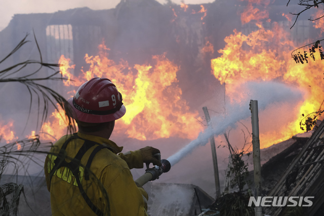 [샌버너디노=AP/뉴시스] 25일(현지시간)&nbsp; 미 캘리포니아주 리알토 북쪽 샌버너디노 카운티의 라이틀 크리크에서 한 소방관이 '사우스 파이어' 산불로 가정집에 옮겨붙은 불을 끄고 있다. 2021.08.26.