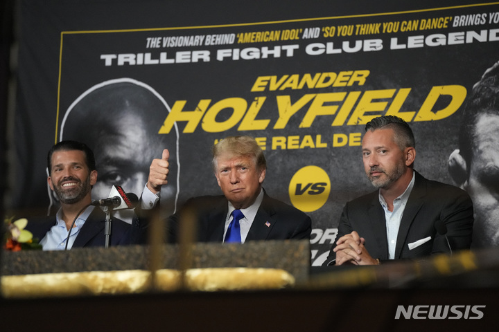 [할리우드(미 플로리다주)=AP/뉴시스]도널드 트럼프 전 미 대통령(가운데)이 11일(현지시간) 플로리다주 할리우드에서 열린 전 헤비급 챔피언 에반더 홀리필드와 전 종합격투기 선수 비터 벨포트와의 복귀전 해설을 준비하면서 환호하는 지지자들에게 엄지손가락을 치켜세우고 있다. 58살의 홀리필드는 이날 44살의 벨포트에게 1회 TKO 패로 고개를 숙였다. 2021.9.13
