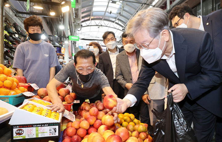 [오산=뉴시스] 경기사진공동취재단 = 이재명 경기지사가 13일 오후 경기도 오산 오색시장에서 추석맞이 전통시장 현장을 방문해 과일을 구입하고 있다. 2021.09.13. photo@newsis.com