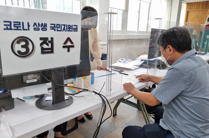 [광주=뉴시스] '코로나 상생 국민 지원금' 오프라인 신청 첫주 주말인 지난 18일 행정복지센터에서 시민이 오프라인 신청 접수를 하고 있다. (사진= 뉴시스 DB) photo@newsis.com *재판매 및 DB 금지