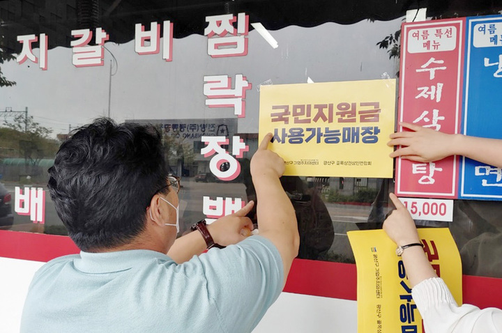 [광주=뉴시스] 광주 광산구의 한 음식점에 전 국민 재난지원금 사용 여부를 알 수 있는 안내 스티커를 붙이고 있다. (사진= 뉴시스 DB) photo@newsis.com *재판매 및 DB 금지