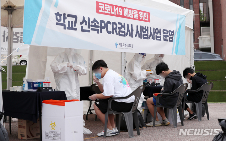 [서울=뉴시스] 지난해 9월28일 오전 서울 종로구 동성고등학교에서 학생들이 등교하며 '신속 자가분자진단 유전자증폭(신속 PCR)' 및 타액을 통한 코로나19 검사를 받고 있다. (사진공동취재단) 2022.01.08. photo@newsis.com