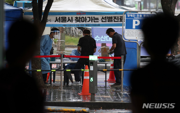 [서울=뉴시스] 조성우 기자 = 6일 오전 코로나19 확진자 집단감염이 발생한 서울 마포구 마포농수산물시장에서 시장 상인들이 찾아가는 선별진료소 모습을 지켜보고 있다. 2021.10.06. xconfind@newsis.com