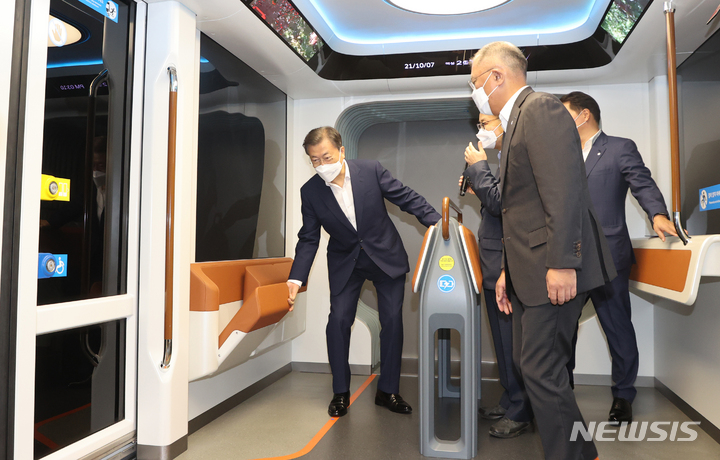 [인천=뉴시스] 전진환 기자 = 문재인 대통령이 7일 인천광역시 서구 현대모비스 수소연료전지공장 투자 예정지에서 열린 수소경제 성과 및 수소 선도국가 비전 보고와 차세대 수소연료전지 특화단지 기공식을 마친 후 수소산업 관련 전시물을 관람하며 현대로템의 수소트램을 시승하고 있다. 2021.10.07. amin2@newsis.com