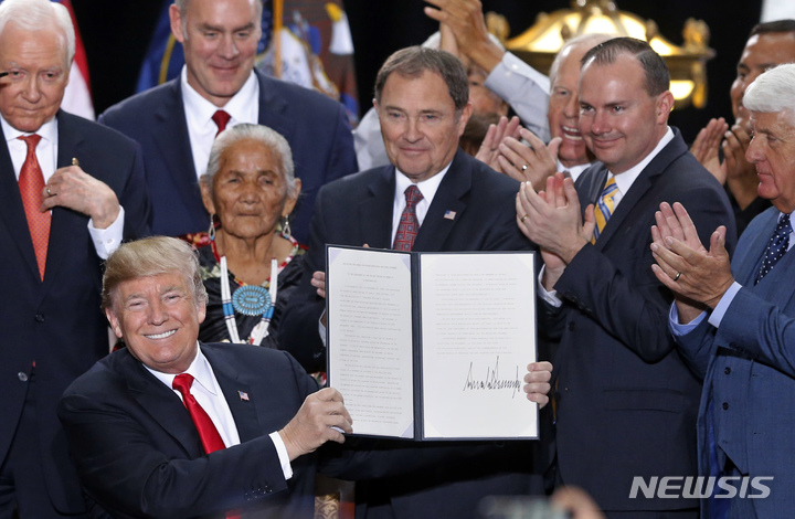 [솔트레이크시티( 미 유타주)=AP/뉴시스] 2017년 12월 4일 유타주로 날아와 유타주의 국립기념물을 대폭 축소하는 행정명령에 서명한 트럼프가 이를 들어보이며 환하게 웃고 있다.&nbsp; 바이든 대통령은 트럼프 행정부의 "해로운"정책들을 바로잡는다며 이를 원상태로 확대한다고 발표했다.