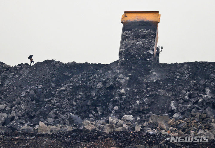 [자리아(인도)=AP/뉴시스]인도 동부 자르칸드주의 자리아에서 2019년 10월23일 한 노동자가 트럭에서 석탄을 내리는 것을 지켜보고 있다. 탄소 배출 제로를 목표로 하는 것은 기후변화에 대한 해결책이 될 수 없다고 미국과 중국에 이어 세계 3위의 탄소 배출국인 인도의 부펜더 야다브 환경부장관이 27일 말했다. 2021.10.28