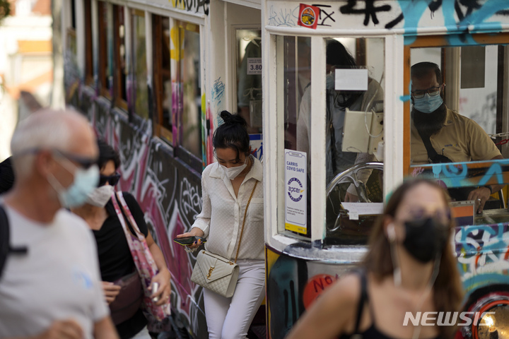 [AP/뉴시스] 9일 포르투갈 리스본에서 시민들이 마스크를 쓰고 차를 타고 내리고 있다. 포르쿠갈 정부는 이날 전국민 85%의 접종완료 목표를 달성했다고 발표했다. 