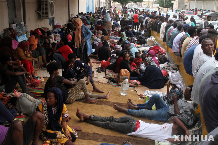 [ 트리폴리( 리비아)= 신화/뉴시스] 리비아 트리폴리시의 알-사라지에 있는 폐쇄된 유엔난민기구 지역센터 앞에서 2021년 10월 수용소를 탈출한 수 천명의 난민들이 대기하고 있다.  리비아 정부는 최근 "불법이민과의 전쟁"으로 700여명의 수단 이민을 본국으로 추방했다. 2025. 07. 20.