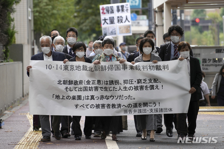 [도쿄=AP/뉴시스] 14일 일본 도쿄에서 북한을 상대로 소송을 제기한 원고들과 그들의 지지자들이 도쿄지방재판소로 향하고 있다. '지상낙원'을 선전하던 북송 사업에 참여했다가 탈북한 5명이 김정은 국무위원장을 상대로 인권 유린에 대한 소송을 제기해 법원은 김 위원장 없이 심리를 진행한다. 북송사업은 재일조선인총연합회가 북한을 '지상낙원'이라고 속여 1959년~1984년까지 일본 국적자 포함 재일 조선인 9만3340명을 북한으로 보낸 사업이다. 2021.10.14.
