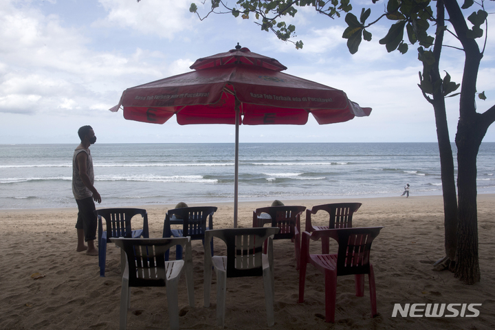 [발리(인도네시아)=AP/뉴시스]14일 한국 등 19개국 관광객들에게 다시 문호를 개방한 인도네시아 발리의 쿠타 해변에서 한 해변 노점상이 손님을 기다리며 의자를 세팅하고 있다. 인도네시아는 13일 밤(현지시간) 늦게 14일부터 발리를 백신 접종을 완료한 19개국 관광객들에게 재개방한다고 발표했다. 2021.10.14