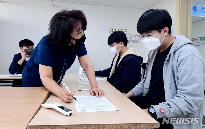 [서울=뉴시스] 사진공동취재단 = 지난 10월18일 오전 서울시 양천구 홍익병원에서 16∼17세 청소년이 코로나19 백신 접종 전 예진표를 작성하고 있다. 2021.10.18. photo@newsis.com