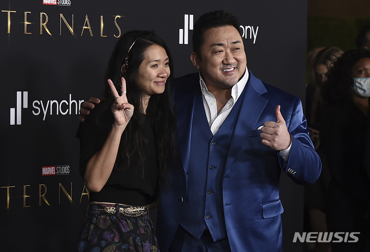 [로스앤젤레스=AP/뉴시스] 배우 마동석(오른쪽)이 18일(현지시간) 미 캘리포니아주 로스앤젤레스에서 열린 영화 '이터널스' 시사회에 도착해 클로이 자오 감독과 포토타임을 갖고 있다. 마동석의 미국 본명은 '돈 리'(Don Lee)로 이번 영화에서 주인공인 길가메시 역을 맡았다. 2021.10.19.
