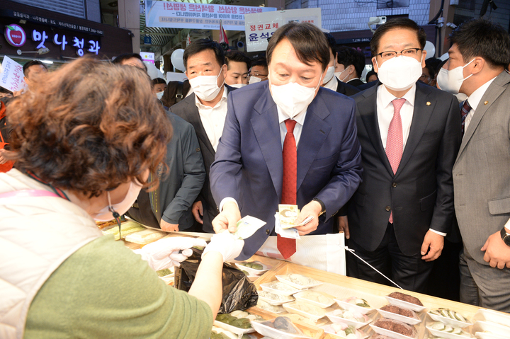 [울산=뉴시스] 배병수 기자 = 윤석열 국민의힘 대선 경선 예비후보가 23일 오전 울산 남구 신정시장을 방문, 떡을 구입하고 있다. 2021.10.23. bbs@newsis.com