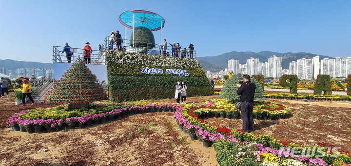 [창원=뉴시스] 강경국 기자 = 제21회 마산국화축제가 27일 창원시 마산합포구 마산해양신도시에서 화려하게 개막한 가운데 시민들이 행사장에서 기념촬영을 하고 있다. 2021.10.27. kgkang@newsis.com