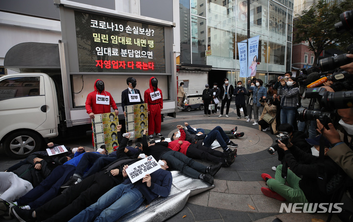 [서울=뉴시스] 조수정 기자 = 한국중소상인자영업자총연합회, 한국자영업자협의회 등 자영업자 단체 회원들이 정부와 건물주 앞에 쓰러진 자영업자를 상징하는 퍼포먼스 하고 있다. 2021.10.27. chocrystal@newsis.com