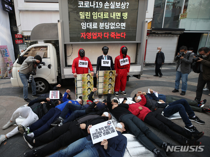 [서울=뉴시스] 조수정 기자 = 한국중소상인자영업자총연합회, 한국자영업자협의회 등 자영업자 단체 회원들이 27일 오전 서울 중구 명동예술극장 앞에서 자영업자 코로나19 손실보상 집행을 앞두고 임대료 분담 대책을 촉구하는 '코로나19 임대료를 멈춰라' 캠페인 돌입 기자회견을 열고 정부와 건물주 앞에 쓰러진 자영업자를 상징하는 퍼포먼스 하고 있다. 2021.10.27. chocrystal@newsis.com