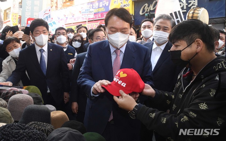 [서울=뉴시스] 국회사진기자단 = 윤석열 국민의힘 대선 경선 후보가 3일 서울 중구 남대문시장을 방문해 모자를 구입하고 있다. 2021.11.03. photo@newsis.com