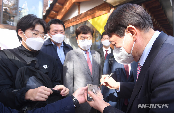 [서울=뉴시스] 정병혁 기자 = 윤석열 국민의힘 대선 후보가 6일 오후 서울  마포구의 한 음식점에서 이준석 대표와 오찬에 앞서 한 시민에게 사인하고 있다. (공동취재사진) 2021.11.06. photo@newsis.com