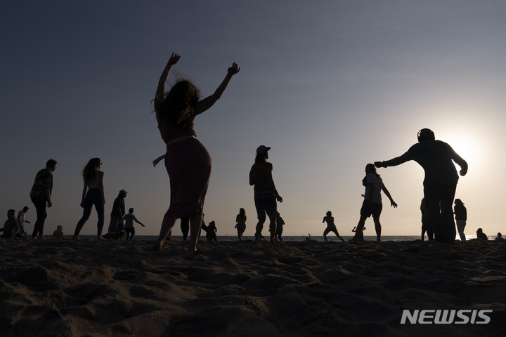 [서울=AP/뉴시스] 캐나다 맥길대 연구팀이 좋아하는 노래를 듣는 것은 신체적 고통을 느끼는 정도를 낮출 수 있다는 연구 결과를 발표했다고 25일(현지시간) 미국 CNN이 보도했다. 2021년 9월29일 미국 로스앤젤레스 베니스 비치에서 열린 행사에서 사람들이 무선 헤드셋으로 음악을 들으며 해변에서 춤을 추고 있는 모습. 기사 내용과는 무관. 2023.10.26.