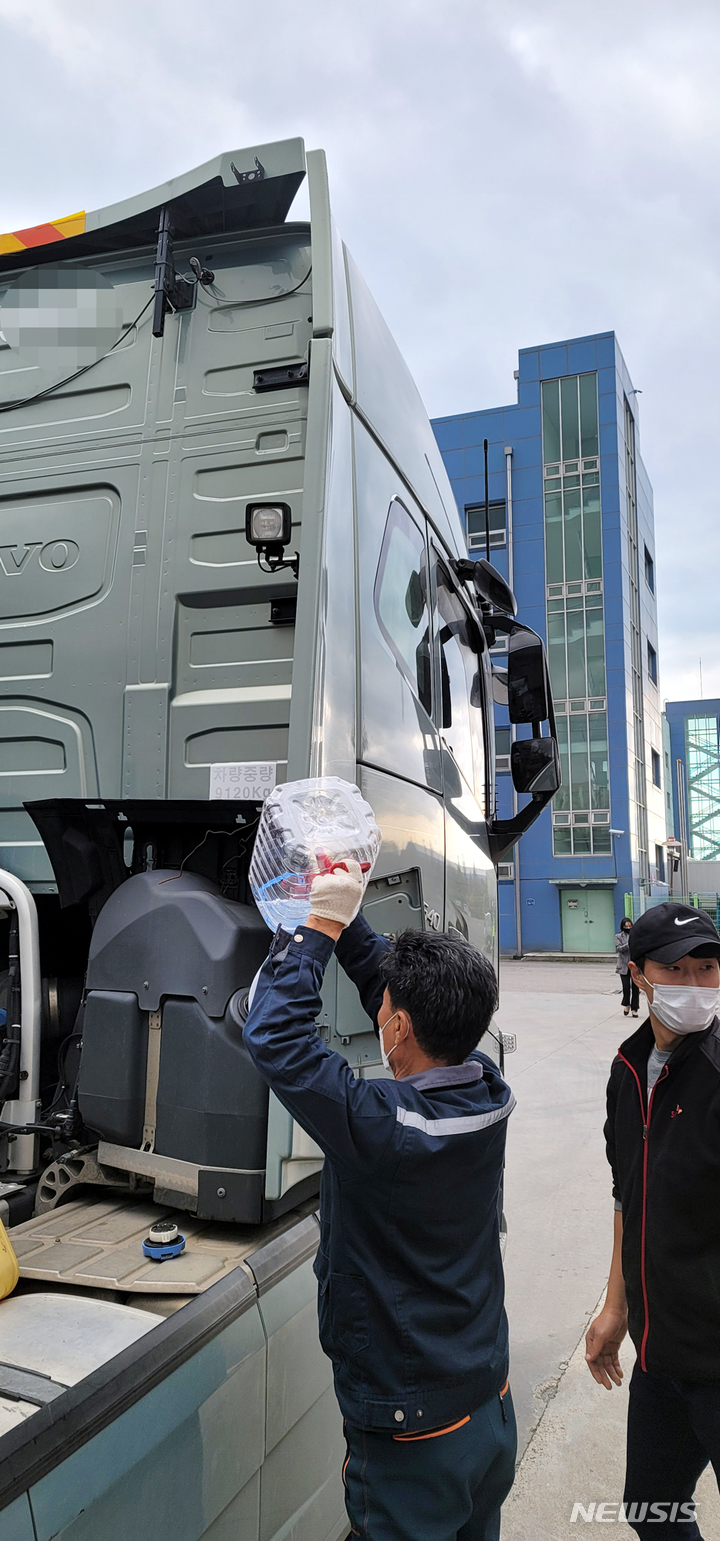 [광양=뉴시스] 김석훈 기자 = 11일 오후 전남 광양시 내트럭 광양황금사업소주유소에서 수출입 컨테이너화물차의 운전기사가 3~4시간을 기다린 끝에 정부가 군으로부터 확보한 요소수를 공급받아 차에 주입하고 있다. 2021.11.11. kim@newsis.com 