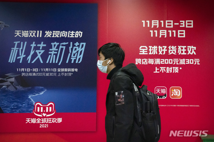 [베이징=AP/뉴시스] 중국 독신자의 날(광군제)인 11일 베이징의 한 지하철역에서 마스크를 쓴 한 시민이 중국의 전자상거래업체 알리바바가 소유한 온라인 쇼핑 플랫폼 '티몰'의 광고판 앞을 지나가고 있다. 중국 최대의 쇼핑 축제인 광군제가 정부의 규제 강화로 올해는 조용한 분위기를 보이는 것으로 알려졌다. 2021.11.11.