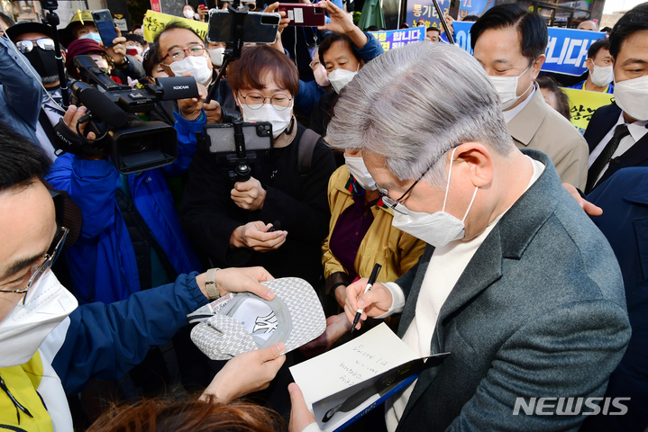 [창원=뉴시스] 차용현 기자 = 매타버스(매주 타는 민생버스)를 타고 전국순회에 나선 더불어민주당 이재명 대통령후보가 13일 오후 경남 창원시 3·15 의거 발원지 기념관앞에서 지지자가 내민 자신의 자서전에 사인을  하고 있다. 2021.11.13. con@newsis.com