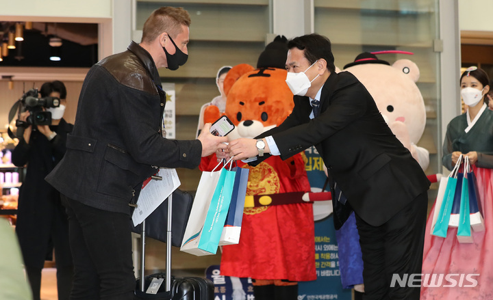 [인천공항=뉴시스] 이영환 기자 = 15일 오전 인천국제공항 제2여객터미널을 통해 싱가포르 관광업계 및 미디어 팸투어단이 입국하자 김경욱 인천국제공항공사 사장이 선물을 증정하고 있다. 이들은 이날부터 한국-싱가포르간 여행안전권역(Vaccinated Travel Lane) 시행에 따라 입국한 관광객들로 코로나19 이후 국내를 찾은 첫 외국인 관광객이다. 2021.11.15. 20hwan@newsis.com