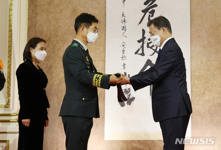 [서울=뉴시스] 전진환 기자 = 문재인 대통령이 16일 청와대 영빈관에서 열린 육해공군 준장 진급자 삼정검 수여식에서 지원정 준장에게 삼정검을 수여하고 있다. 삼정검의 '삼정'은 육·해·공군이 일치하여 호국·통일·번영의 3가지 정신 달성을 의미한다. 이날 문 대통령은 76명에게 삼정검을 수여했다. 2021.11.16. amin2@newsis.com