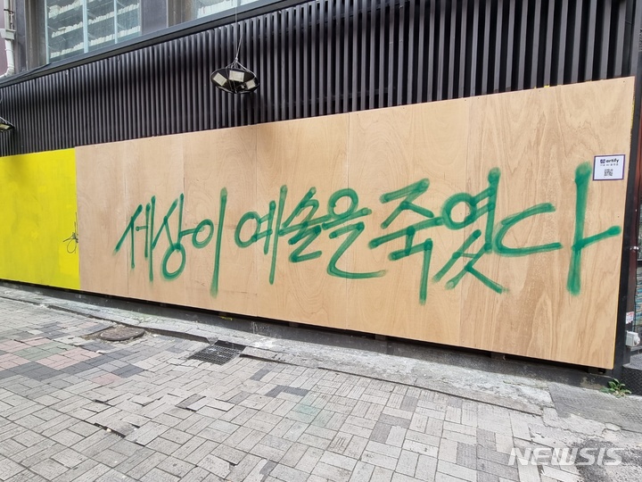 [서울=뉴시스]임하은 수습기자=중년 여성과 손바닥 王(왕)자, 개·사과, 전두환 전 대통령으로 추정되는 인물이 그려져 있던 종로구 중고서점의 외벽이 17일 오전 합판으로 가려졌다. 2021. 11. 17. 