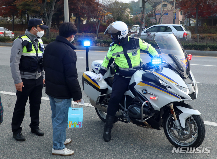 [전주=뉴시스] 김얼 기자 = 2022학년도 대학수학능력시험일인 18일 전북 전주시 전주사대부고 앞에서 고사장을 착각한 수험생이 경찰의 도움을 받기 위해 오토바이로 향하고 있다. 2021.11.18. pmkeul@newsis.com