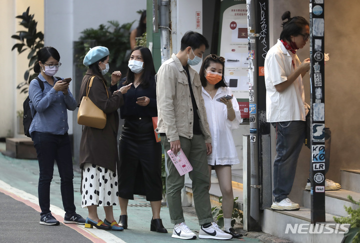 [타이베이=AP/뉴시스] 대만 수도 타이베이 시내에서 21일 전문점에 들어가쇼핑하려는 손님들이 코로나19 예방을 위해 마스크를 쓴 채 줄을 서서 기다리고 있다. 2021.11.21 