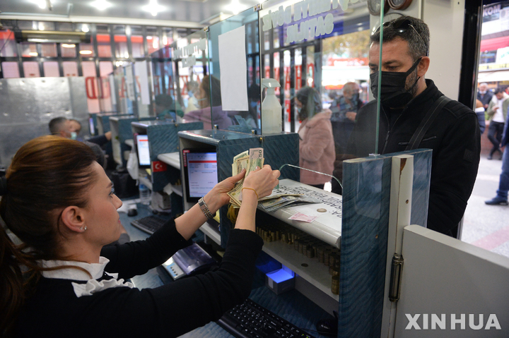 [앙카라=신화/뉴시스] 23일(현지시간) 터키 앙카라의 한 환전소에서 손님이 환전하고 있다. 레제프 타이이프 에르도안 터키 대통령의 기준금리 인하 압박에 리라화의 가치가 하루 동안 최대 18% 폭락해 역대 최저치를 기록했다. 중앙은행의 기준금리 인하는 시중 통화량을 늘려 물가가 상승하고, 외화 대비 자국 통화의 가치가 하락한다. 2021.11.24.