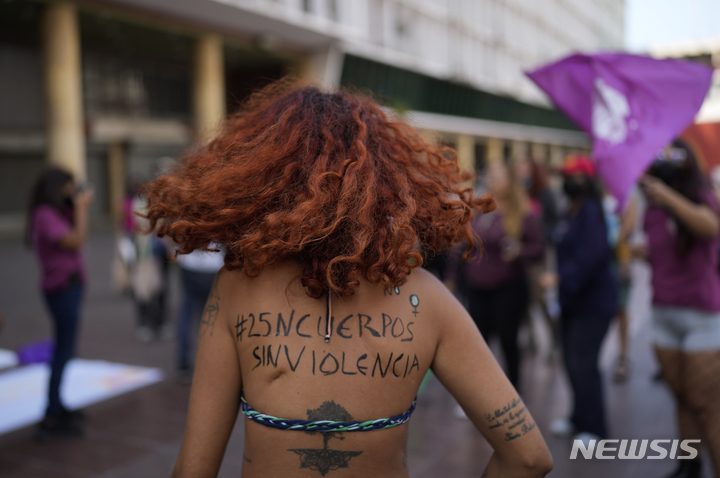 [카라카스=AP/뉴시스] 세계 여성폭력 추방의 날인 25일(현지시간) 베네수엘라 카라카스에서 자신의 등에 "폭행 없는 몸"이라 쓴 한 여성이 시위에 참여하고 있다. 11월 25일은 1999년 유엔총회에서 정한 세계 여성폭력 추방의 날이다. 2021.12.27.