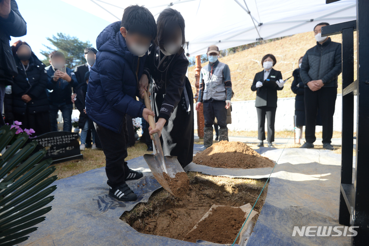 [광주=뉴시스] 김혜인 기자 = 26일 오전 광주 북구 운정동 국립 5·18민주묘지 2묘역에서 이광영씨 유해 안장식이 열린 가운데 유족들이 허토하고 있다. 이씨는 5·18 당시 부상자를 구조하다 계엄군이 쏜 총에 맞아 하반신이 마비됐으며 계엄군 헬기 난사 목격을 증언했다. 2021.11.26.hyein0342@newsis.com