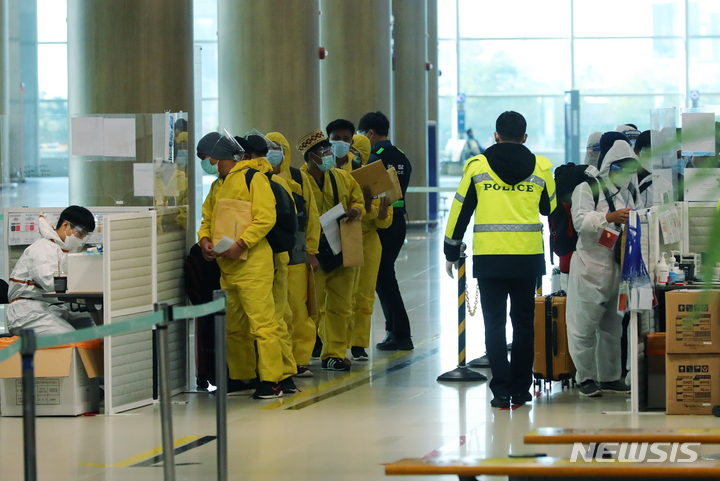 [인천공항=뉴시스] 배훈식 기자 = 코로나19 변이 바이러스 오미크론 유입 차단을 위해 남아공 등 8개국 발 외국인 입국이 제한된 29일 오전 인천국제공항 제1터미널에서 방호복을 착용하고 입국한 외국인들이 행선지 이동 수단 등을 확인하기 위해 대기하고 있다. 2021.11.29. dahora83@newsis.com