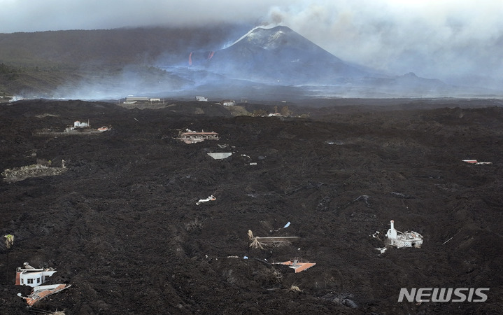 [라팔마=AP/뉴시스] 29일(현지시간) 스페인 카나리아제도 라팔마섬의 쿰브레 비에하 화산이 70일째 분출을 이어가면서 흘러내린 용암이 주택가를 뒤덮고 있다. 스페인 당국은 이 화산의 몇몇 새로운 분화구에서 용암이 분출, 산등성이를 따라 빠르게 흘러내리면서 주민들이 대피한 땅과 기반시설, 주택 등에 또다시 큰 피해를 줄 수 있다고 경고했다. 2021.11.30.