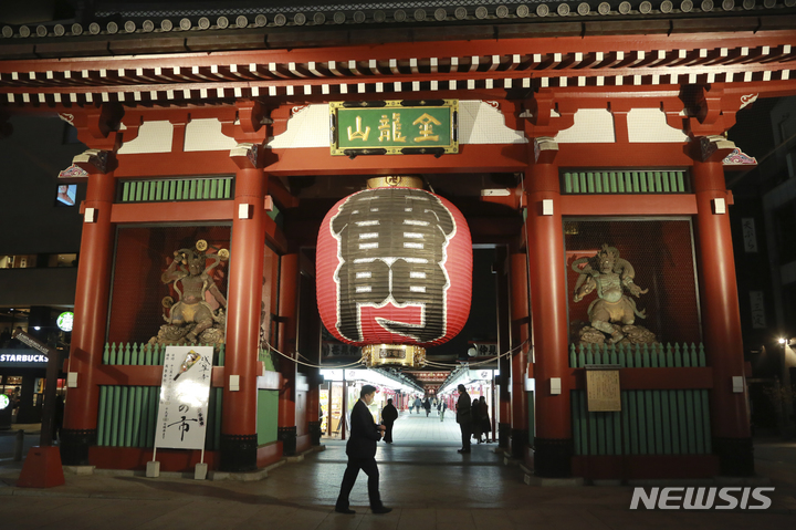 [도쿄=AP/뉴시스]지난 11월 30일 도쿄 아사쿠사의 관광지인 '가미나리몬' 앞을 마스크를 착용한 방문객들이 지나가고 있다. 2021.12.14.