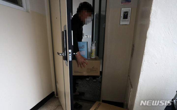 [서울=뉴시스] 이영환 기자 = 2일 오후 서울 중랑구의 한 아파트에서 코로나19 재택치료중인 시민이 중랑구보건소에서 전달한 재택치료용 건강관리 세트(의약품, 산소포화도 측정기, 체온계, 손소독제, 세척용 소독제 등)를 수령하고 있다. 2021.12.02. 20hwan@newsis.com